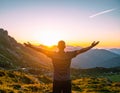 Rejoicing man with beautiful scenic mountain sunset landscape on background. Royalty Free Stock Photo