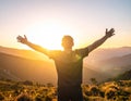 Rejoicing man with beautiful scenic mountain sunset landscape on background. Royalty Free Stock Photo
