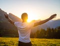 Rejoicing man with beautiful scenic mountain sunset landscape on background. Royalty Free Stock Photo