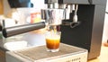 Espresso machine brewing coffee into a small glass. The machine is made of stainless steel Royalty Free Stock Photo