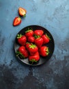 Fresh strawberries on a small black plate against a blue plaster design board. Royalty Free Stock Photo