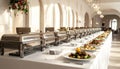 Elegant Buffet Setup with Chafing Dishes and Fresh Salads in a Grand Ballroom bathed in Sunlight Royalty Free Stock Photo
