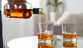 Pouring tasty whiskey from bottle into glass at mirror table, closeup Royalty Free Stock Photo