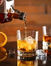 Pouring tasty whiskey from bottle into glass at mirror table, closeup Royalty Free Stock Photo