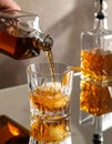 Pouring tasty whiskey from bottle into glass at mirror table, closeup Royalty Free Stock Photo