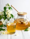 A jar of honey and a glass of hot jasmine tea in a teapot on a white wooden background Royalty Free Stock Photo