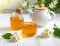 A jar of honey and a glass of hot jasmine tea in a teapot on a white wooden background Royalty Free Stock Photo