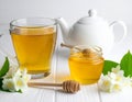 A jar of honey and a glass of hot jasmine tea in a teapot on a white wooden background Royalty Free Stock Photo
