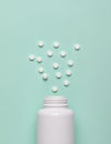 Medicine pills spilled from white plastic bottle isolated on green background. Royalty Free Stock Photo