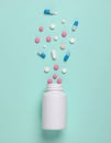 Medicine pills spilled from white plastic bottle isolated on green background. Royalty Free Stock Photo