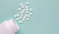 Medicine pills spilled from white plastic bottle isolated on green background. Royalty Free Stock Photo