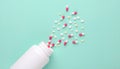 Medicine pills spilled from white plastic bottle isolated on green background. Royalty Free Stock Photo