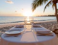 A table set for dinner on a sandy beach during sunset Royalty Free Stock Photo