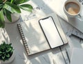 A neatly arranged workspace featuring a smartphone placed on an open spiral-bound notebook with lined pages. Royalty Free Stock Photo