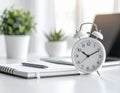 A minimalist desk setup features a white analog alarm clock with black hands and numbers, showing 2 o\'clock Royalty Free Stock Photo