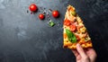 Sliced slice of pizza in hand with cheese, trout, tomatoes cherry, olives and shrimps Royalty Free Stock Photo
