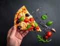Sliced slice of pizza in hand with cheese, trout, tomatoes cherry, olives and shrimps Royalty Free Stock Photo