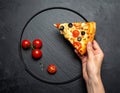 Sliced slice of pizza in hand with cheese, trout, tomatoes cherry, olives and shrimps Royalty Free Stock Photo