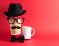 Men\'s faces made of cups, fake mustaches, glasses, hat and bow tie on red background. Royalty Free Stock Photo