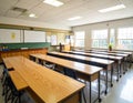 A spacious classroom with several rectangular wooden desks arranged in rows Royalty Free Stock Photo