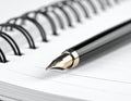 A close-up image of a fountain pen resting on an open spiral-bound notebook Royalty Free Stock Photo
