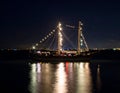 A sailboat illuminated with string lights sails at night, reflecting in the dark water Royalty Free Stock Photo