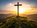Wooden cross atop a grassy hill at sunset, overlooking a tranquil landscape of rolling hills Royalty Free Stock Photo