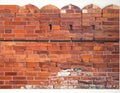 Red brick wall featuring decorative crenellations at the top Royalty Free Stock Photo