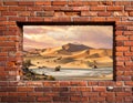 A red brick wall features a rectangular opening framing a desert landscape Royalty Free Stock Photo