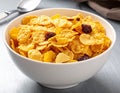 A white ceramic bowl filled with a breakfast cereal mix of golden-brown corn flakes and dark raisins Royalty Free Stock Photo