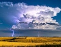 A dramatic cumulonimbus cloud formation with bolts of lightning striking a flat, open field Royalty Free Stock Photo