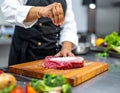 An experienced chef salts raw fresh beef before roasting or barbecuing. Working Royalty Free Stock Photo