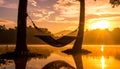 Sunset with hammock in silhouette shadow with orange light effect. Royalty Free Stock Photo