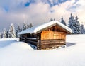 Log cabin surrounded by thick snow in a pine forest. The cabin is made of wood logs with a sloped roof blanketed in snow Royalty Free Stock Photo