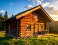 A rustic wooden cabin in a forested area during sunset Royalty Free Stock Photo