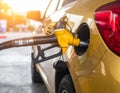 A yellow car is being refueled at a gas station using a black and yellow fuel nozzle Royalty Free Stock Photo