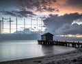 Coastal scene at sunset with a weathered wooden pier extending into calm water Royalty Free Stock Photo