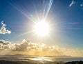 Bright sun in a clear blue sky over a coastal landscape Royalty Free Stock Photo