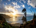 Sun setting over the Pacific Ocean at a coastal location, featuring rugged cliffs flanking a sandy beach Royalty Free Stock Photo