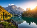 Crystal-clear lake reflecting majestic mountains at sunrise, surrounded by dense forests with autumn foliage Royalty Free Stock Photo