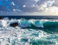 Powerful ocean waves crash against rugged rocks under a partly cloudy sky Royalty Free Stock Photo