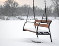 Metal and wooden swing covered in snow, suspended by chains Royalty Free Stock Photo