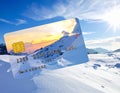 A credit card with the appearance of a snowy mountain scene overlaps an image of a snow-covered landscape Royalty Free Stock Photo