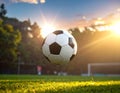 Soccer ball mid-air over a grassy field, backlit by a setting sun Royalty Free Stock Photo