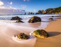 Rocky beach scene with moss-covered stones in the foreground and soft, swirling waves Royalty Free Stock Photo