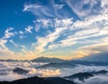 Rolling mountain peaks rise through a sea of fluffy clouds under a vibrant sky filled with wispy cirrus clouds Royalty Free Stock Photo