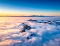 Aerial view of a mountain landscape under a sea of clouds during sunrise or sunset Royalty Free Stock Photo