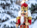 Christmas Nutcracker King wearing crown and holding scepter, snow covered evergreen t Royalty Free Stock Photo