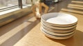 Stack of plates on a table near window, wooden background Royalty Free Stock Photo