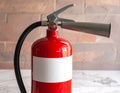 Red fire extinguisher with a metallic nozzle and pressure gauge, resting on a marble surface Royalty Free Stock Photo